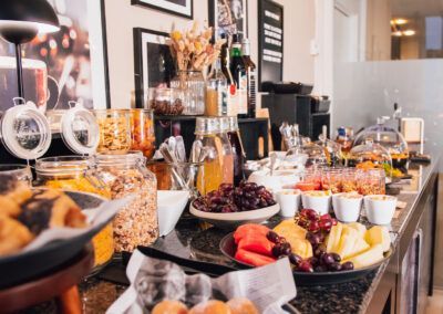 Breakfast buffet with pastries, fruit, cereal, and drinks.