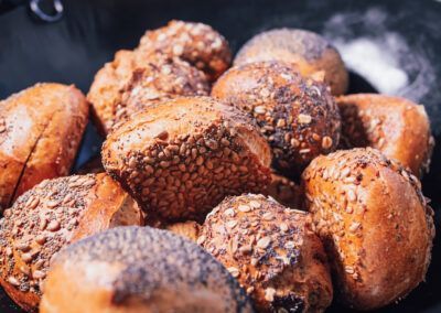 Variety of crusty, seeded rolls in a black bowl.