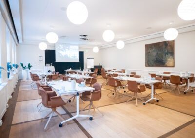 Conference room with tables, chairs, projector, and round white lights.