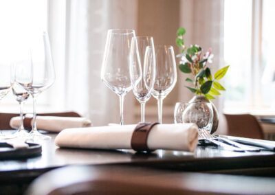 Table setting in a restaurant: wine glasses, rolled napkin with band, small flower vase.