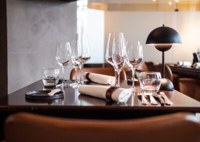 Elegant restaurant table setting with wine glasses, napkins, silverware, and a modern lamp.
