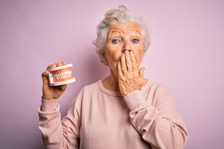 Old Woman Holding Dentures — Greenville, NC — Natalie B. McCarthy, DDS, PA