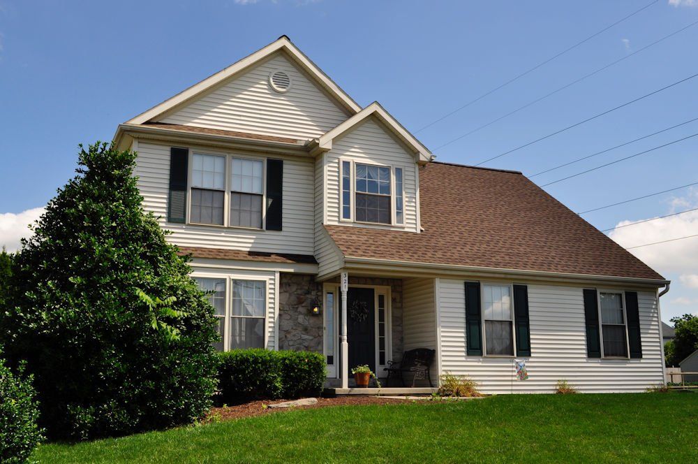 A large white house with a brown roof and black shutters