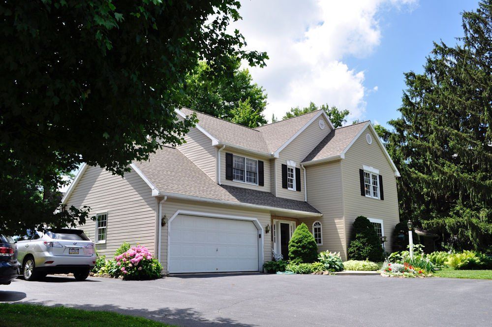 A white car is parked in front of a large house