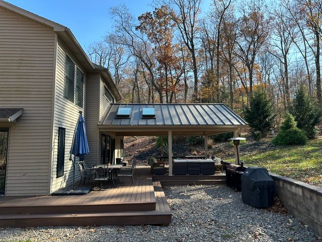 A house with a new covered deck or patio roof and a hot tub in the backyard.