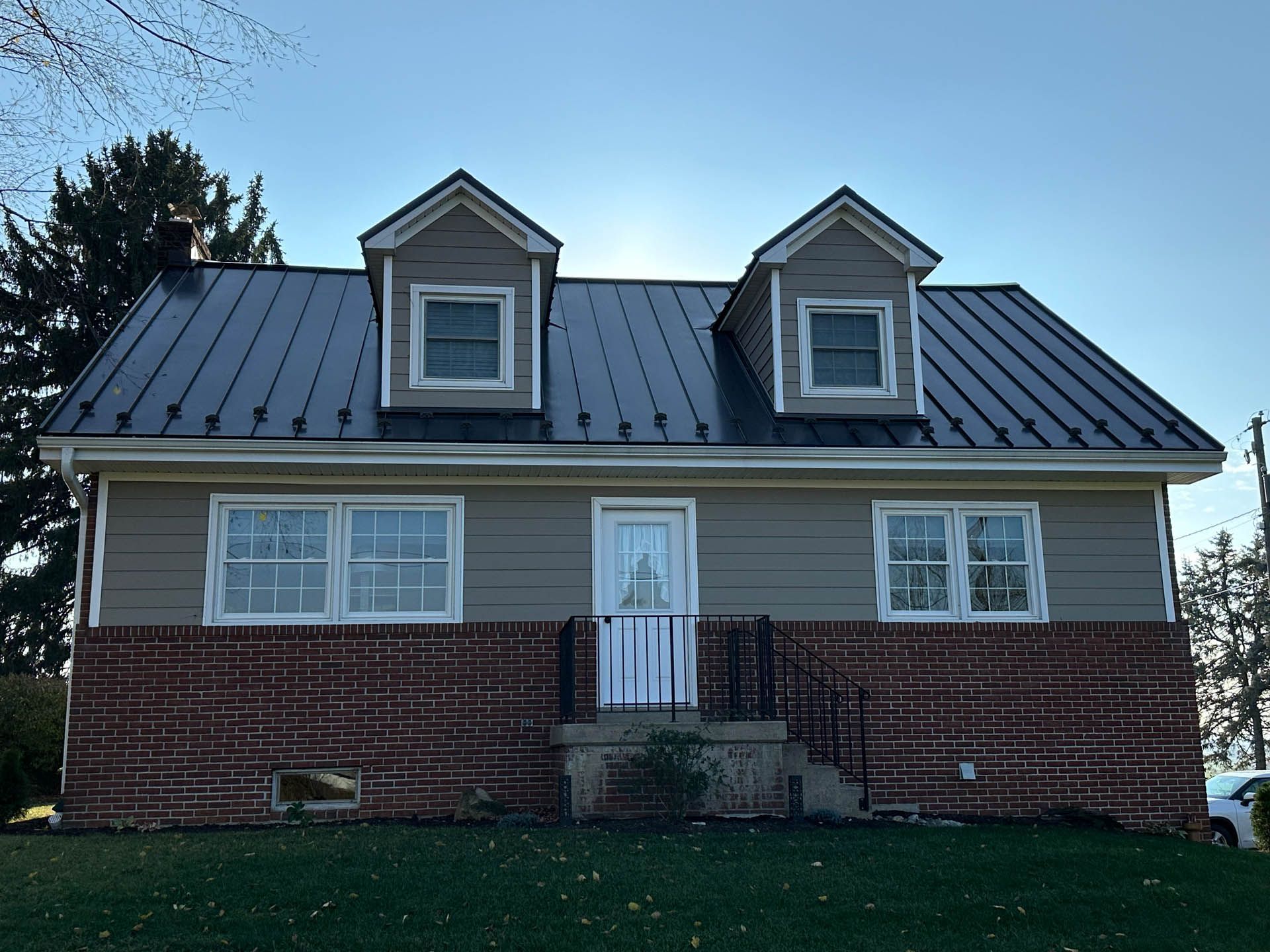 A brick house with a metal roof and a black roof.