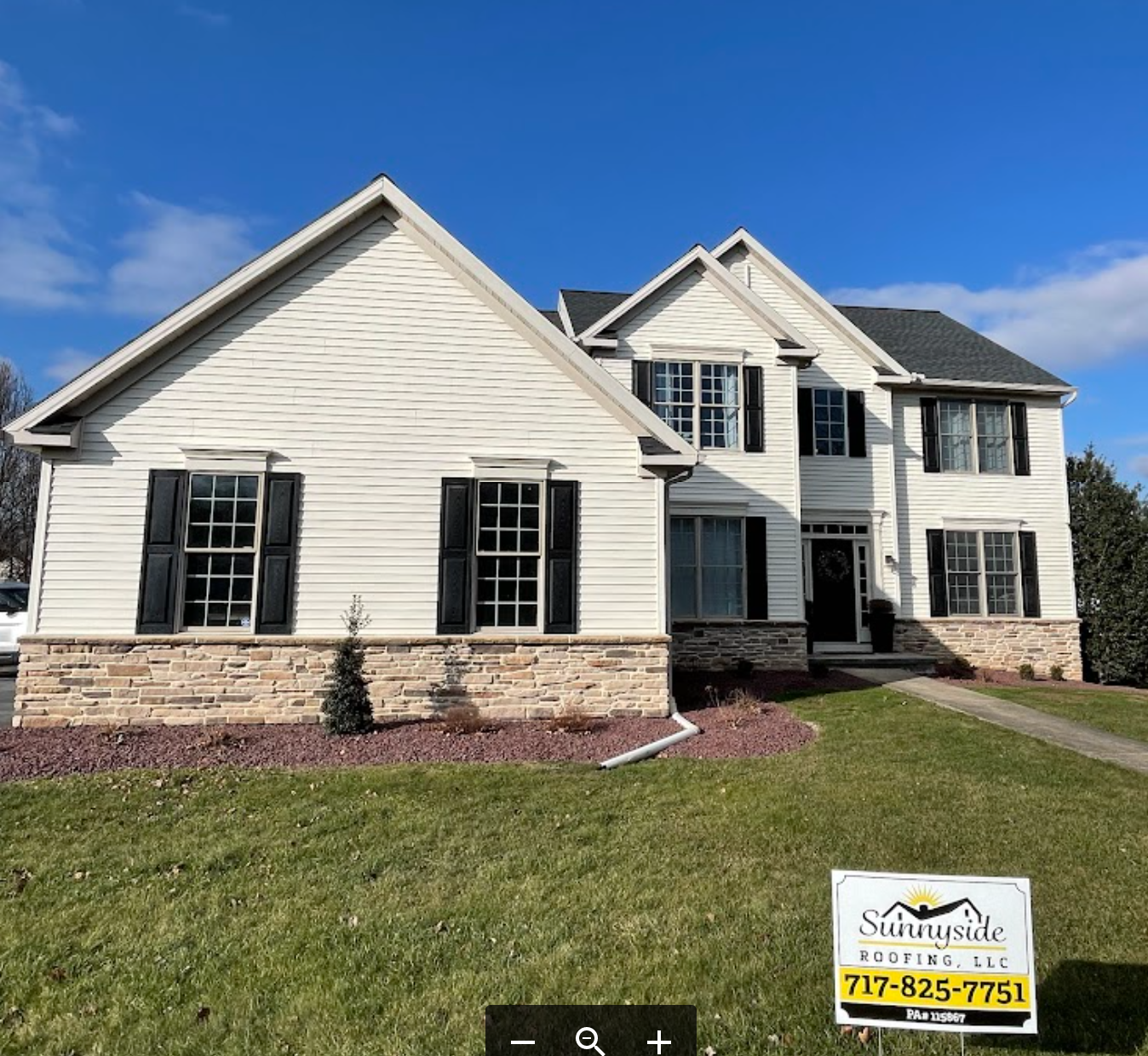 A large white house with a sale sign in front of it that says sunnyside roofing llc