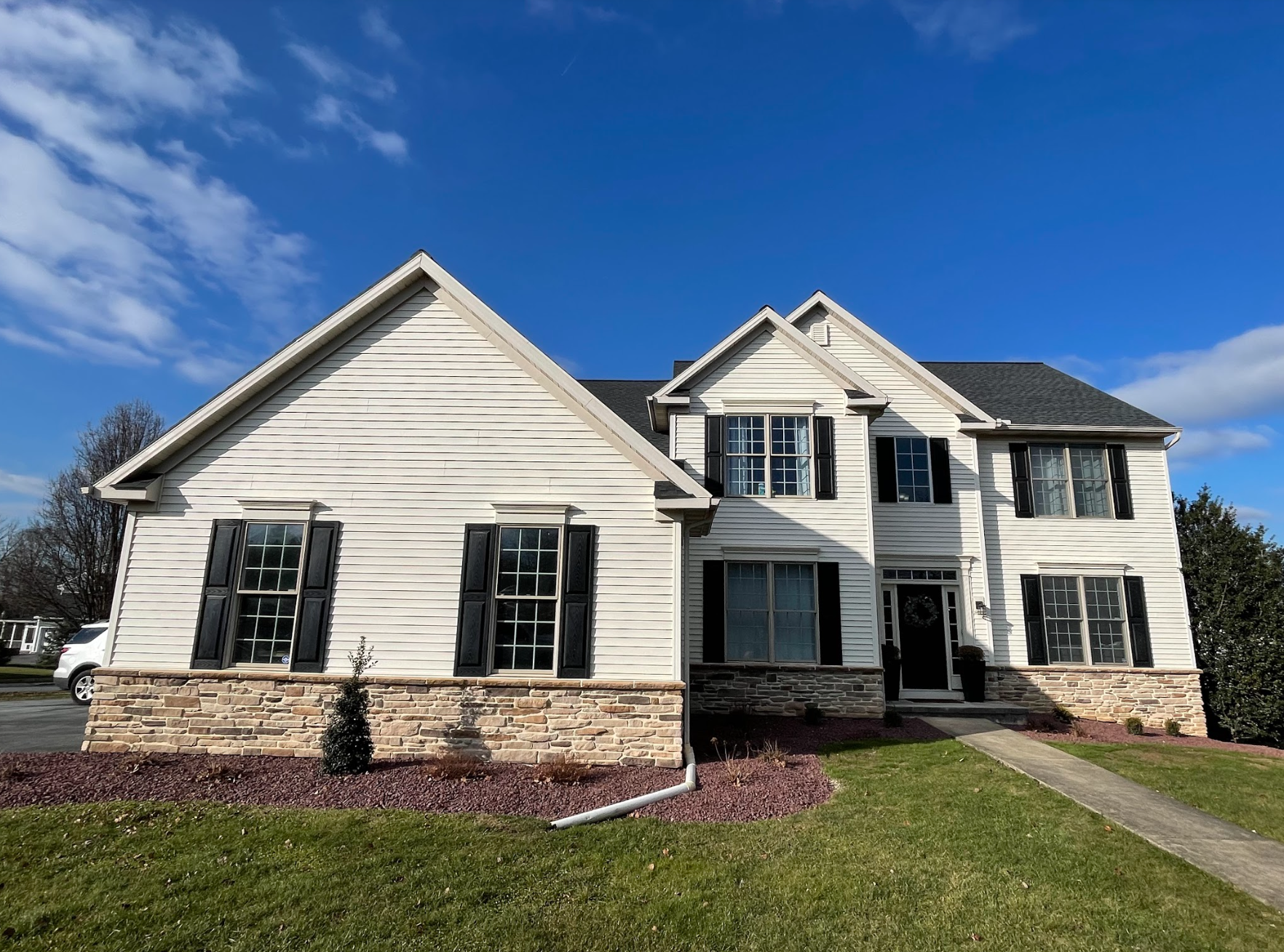 A large white house with black shutters is for sale.