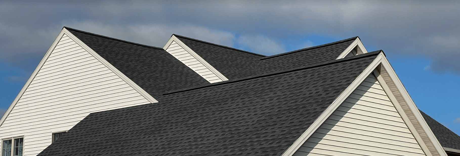 A white house with a black roof and a blue sky in the background.