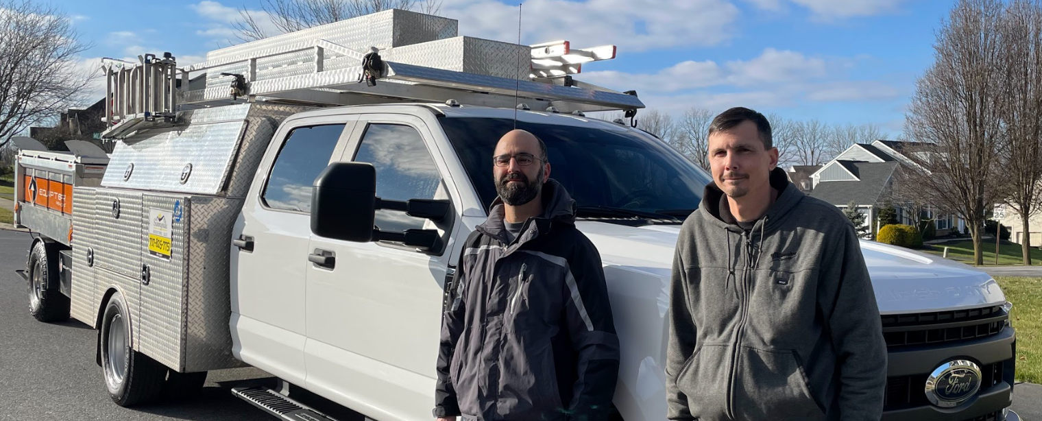 Two men are standing in front of a white truck from Sunnyside roofing.