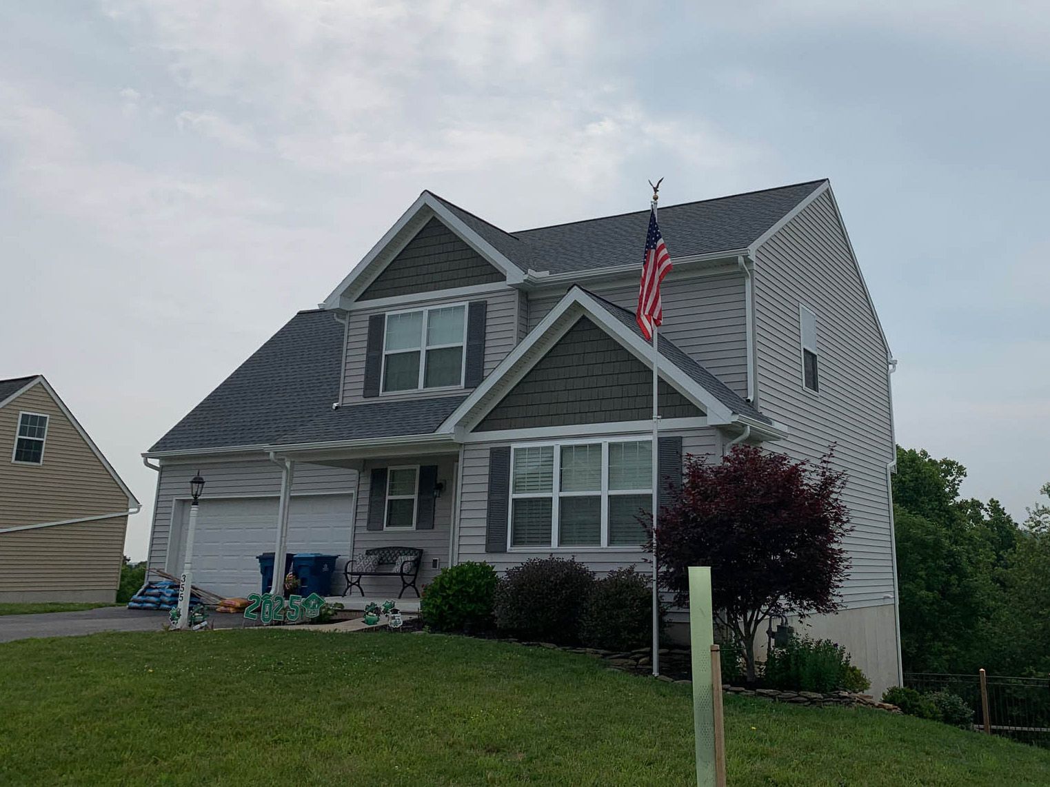 A large white house with a new gray roof and an american flag