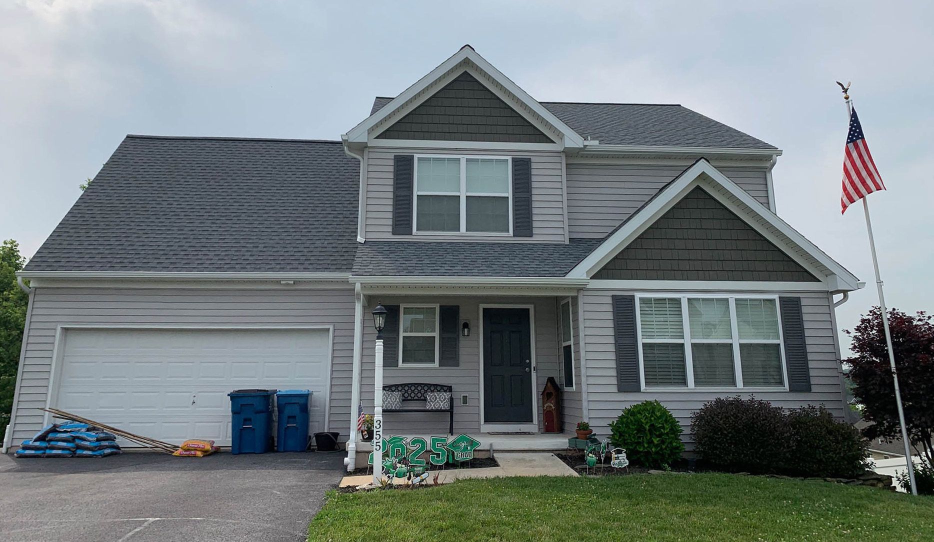 A large house with a gray roof and a flag in front of it installed by sunnyside roofing