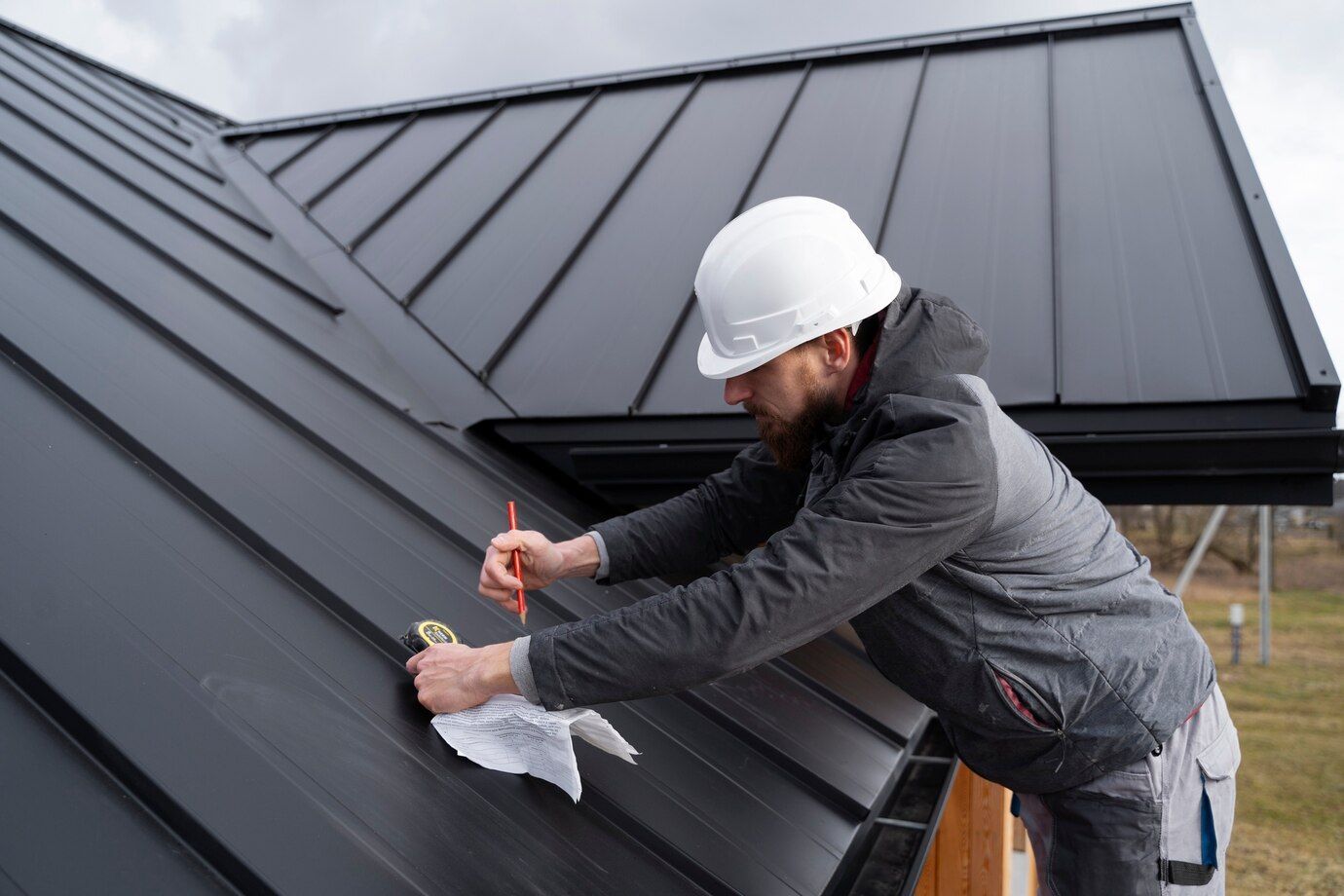 a man is measuring the metal roof of a house with a tape measure .