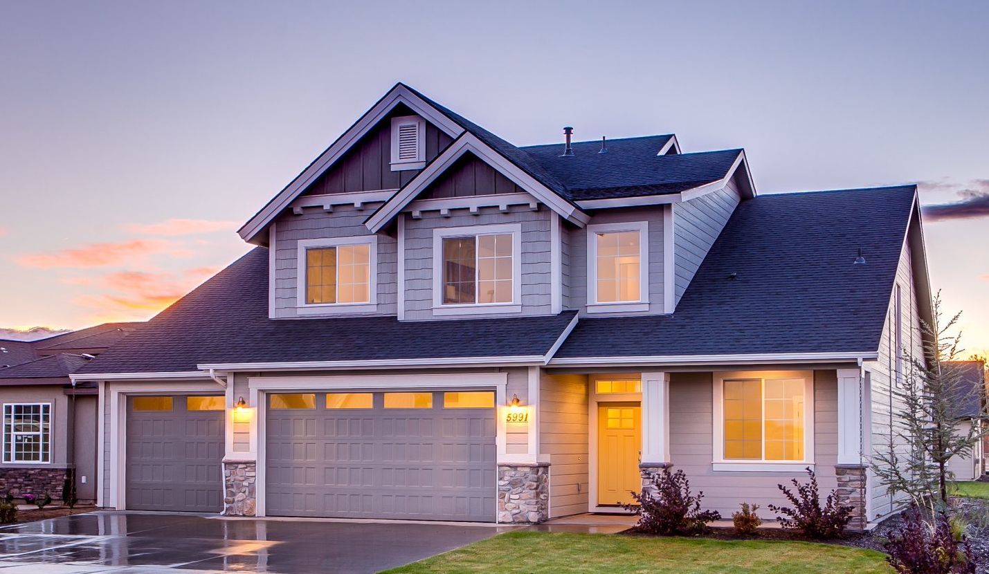 A large house with a garage and a driveway is lit up at night.