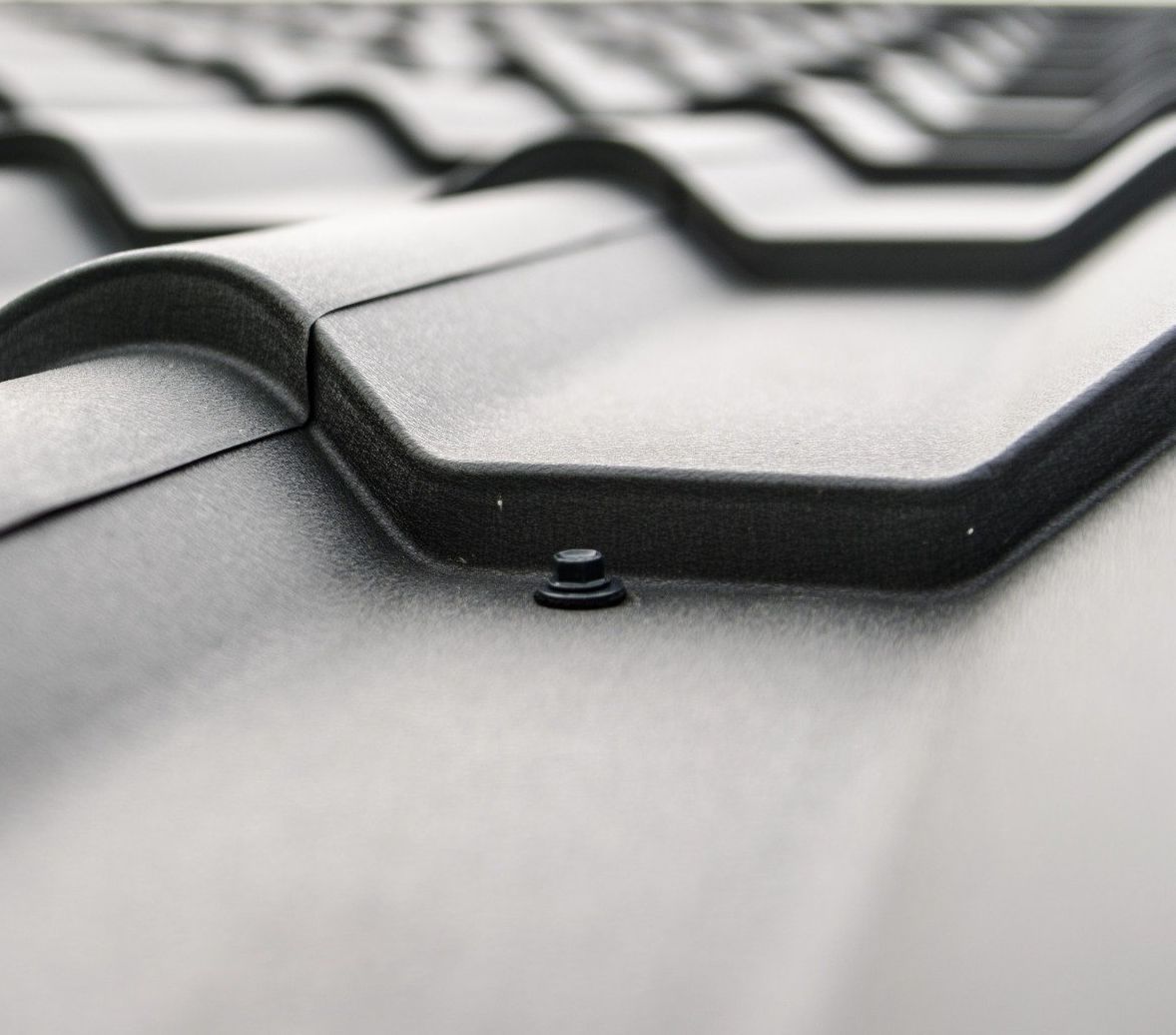 A close up of a black roof with a screw in it.