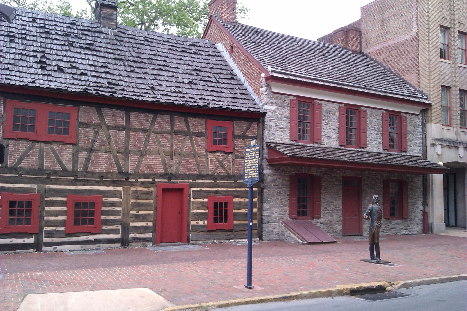 A statue of a man stands in front of a stone building