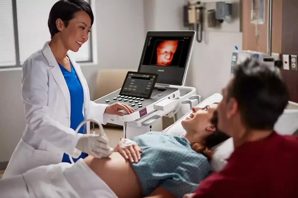 doctor uses ultrasound machine on pregnant patient while man watches