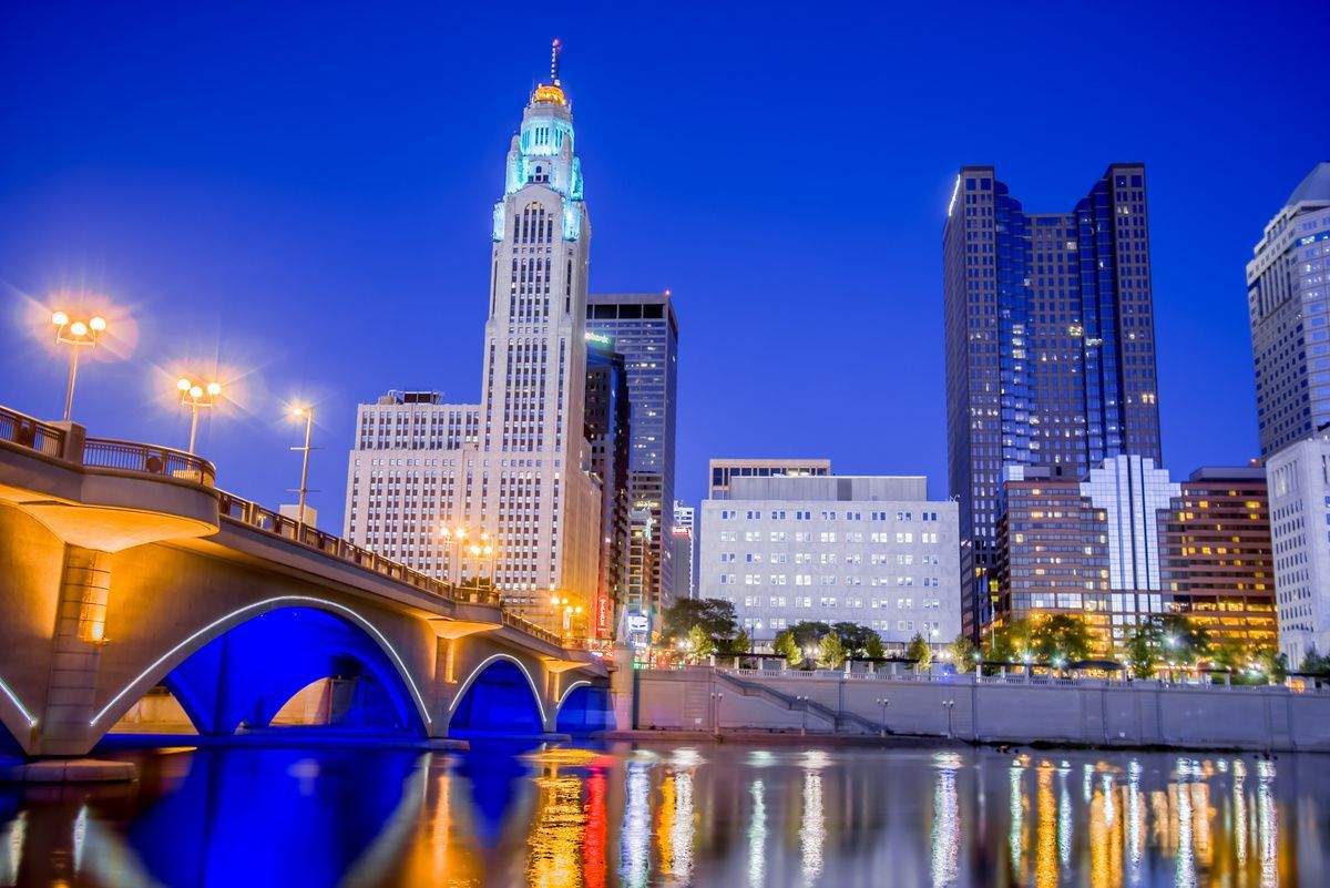 bridge over water with city skyline behind it