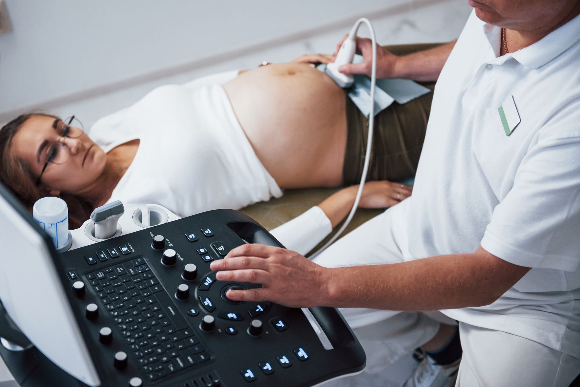 Doctor using women's health ultrasound device on pregnant patient