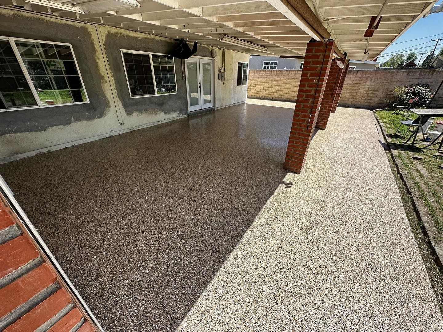 Covered patio and walkway with a decorative stone surface, brick columns and walls.