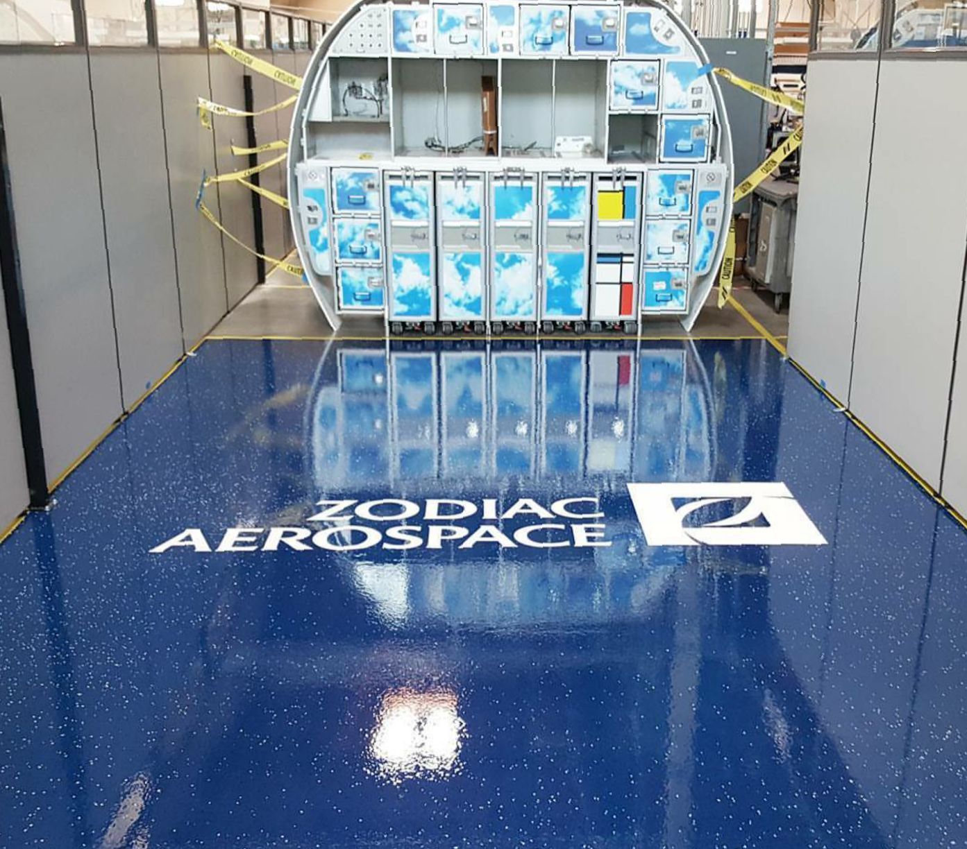 Zodiac Aerospace logo on a shiny blue floor, reflecting the front of an aircraft cabin.