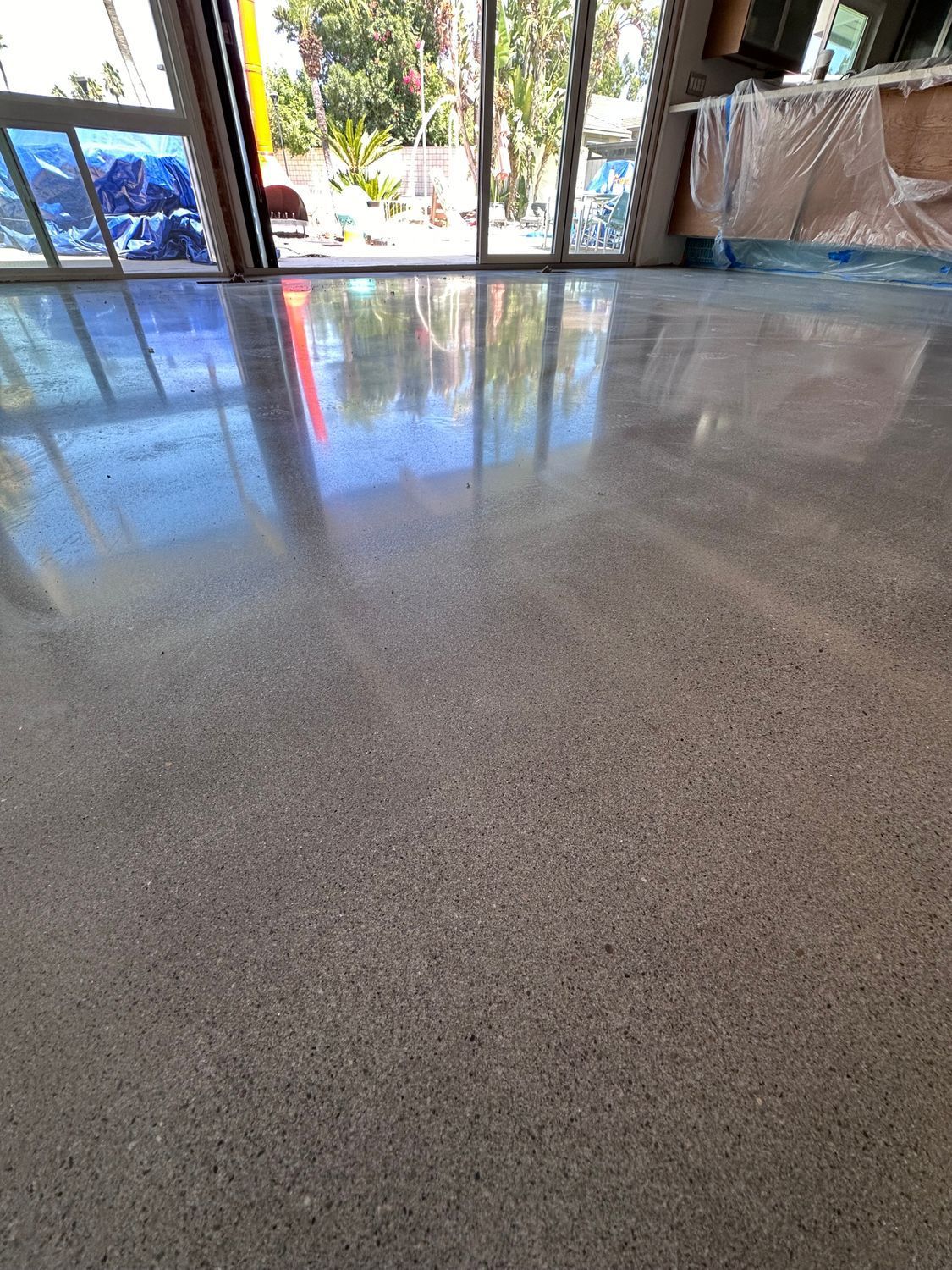 Polished gray concrete floor reflects natural light from large windows.