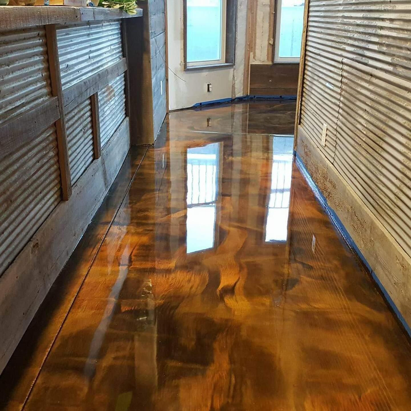 Metallic gold-colored epoxy floor in a room, reflecting light. Walls have corrugated metal and wood paneling.