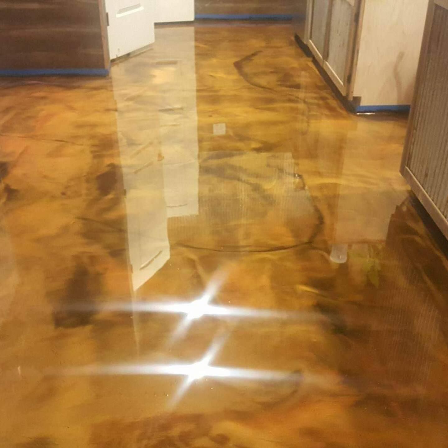 Metallic gold epoxy floor reflects light in room with cabinets and door.