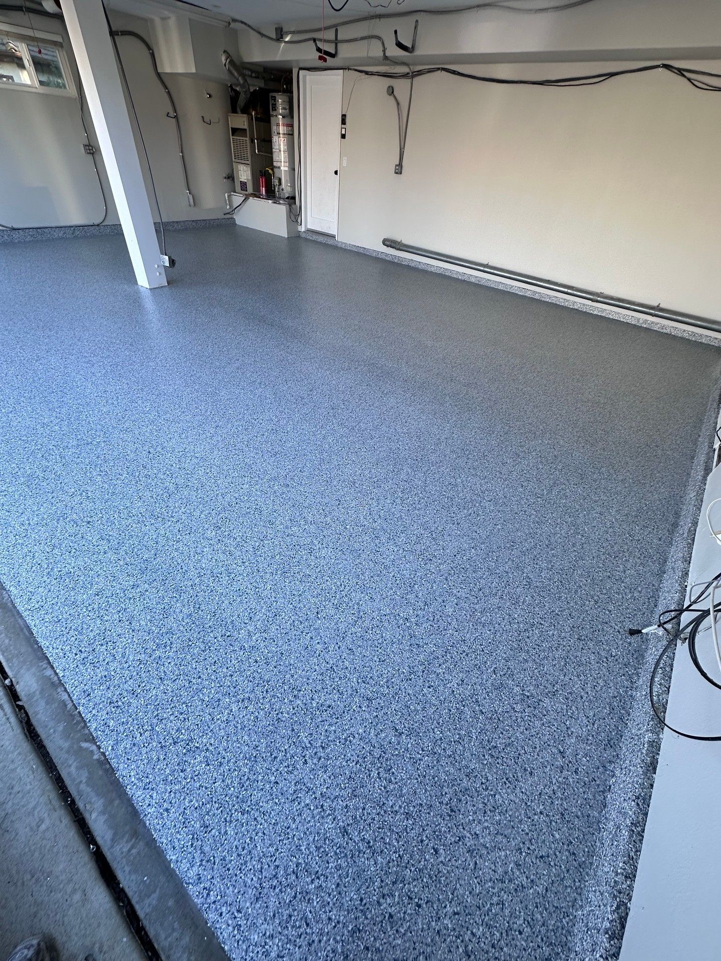 Garage with gray epoxy floor, white walls, and a support beam. Electrical wiring visible.