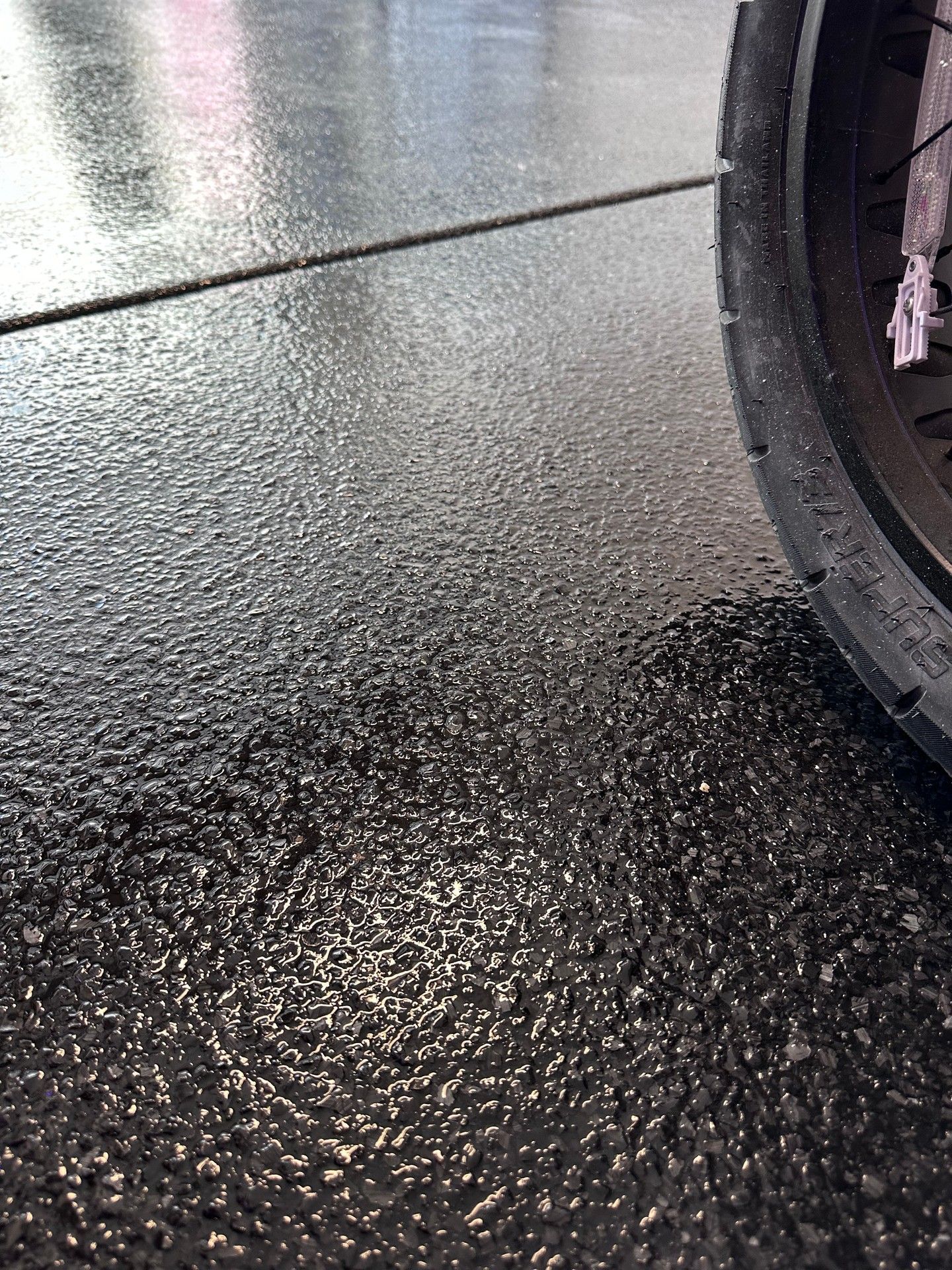 Black tire on textured black flooring with a horizontal seam.