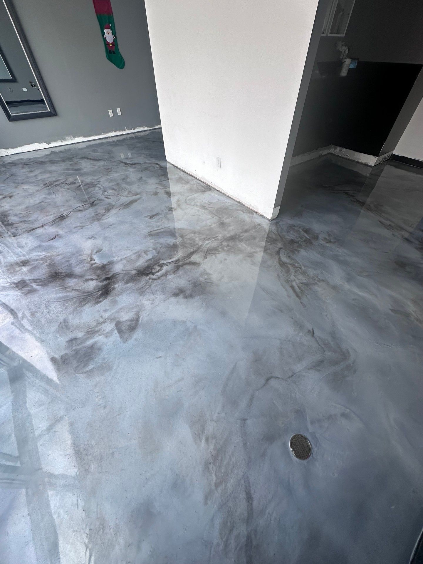 Metallic epoxy flooring, predominantly silver with darker marbled accents. Reflective surface.