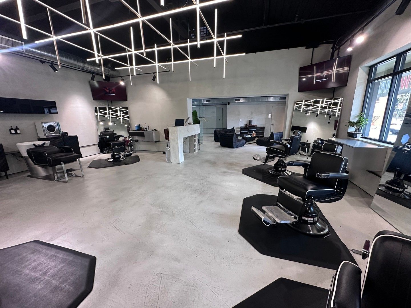 Barber shop interior with black barber chairs, mirrors, and modern lighting.