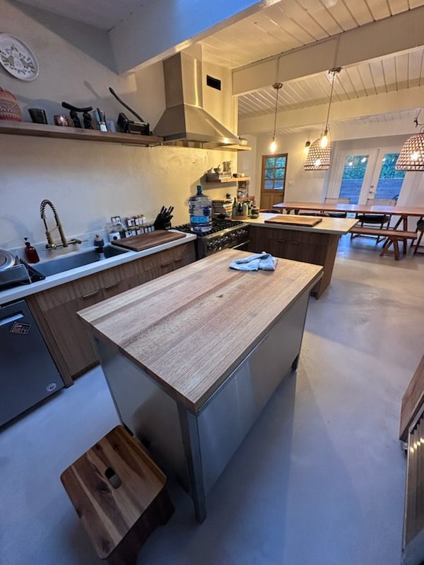 Spacious kitchen with wood counters, stainless steel appliances, island, and dining area with wooden tables.