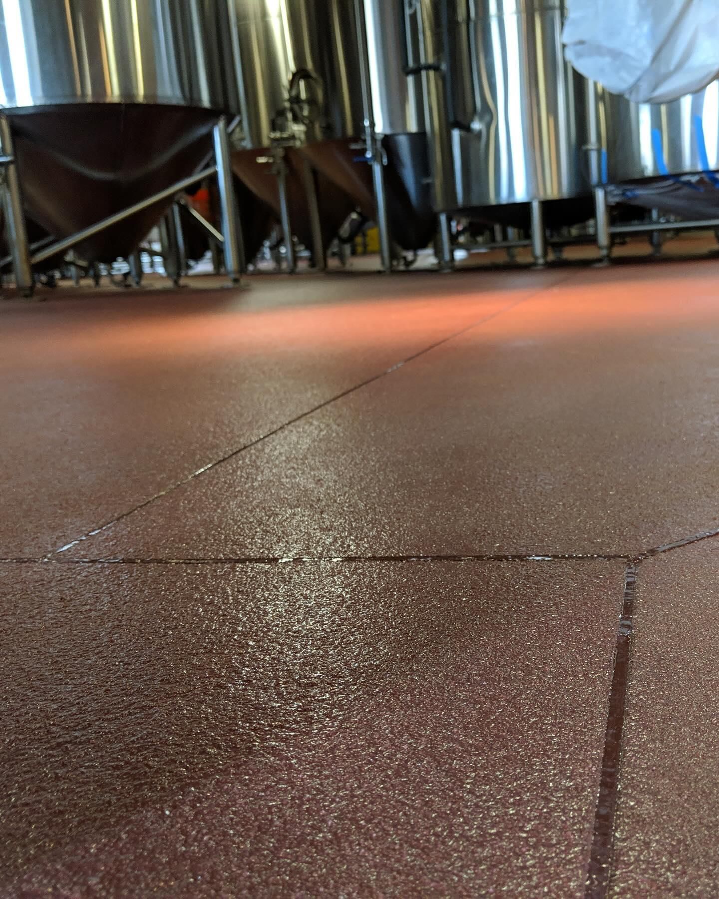 Red industrial floor with tanks in the background, possibly a brewery.