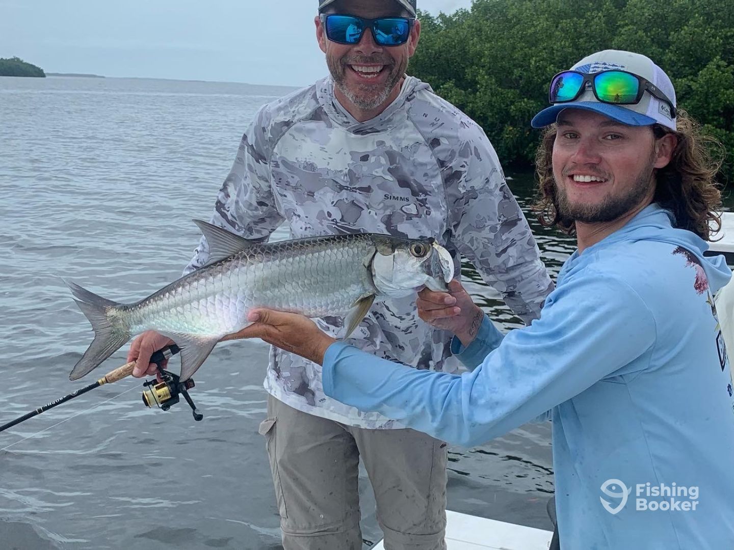 Two men are standing on a boat holding a fish.