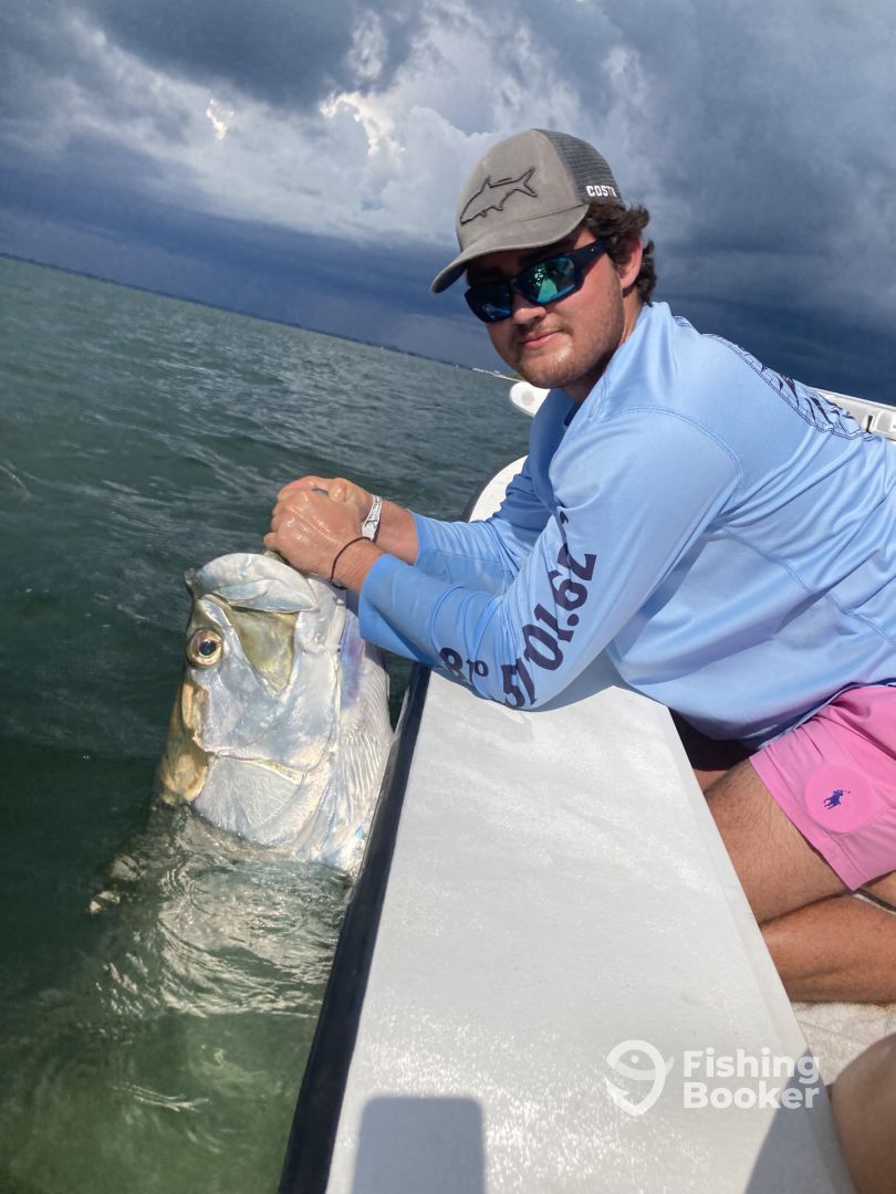 A man is sitting on a boat with a fish in the water.