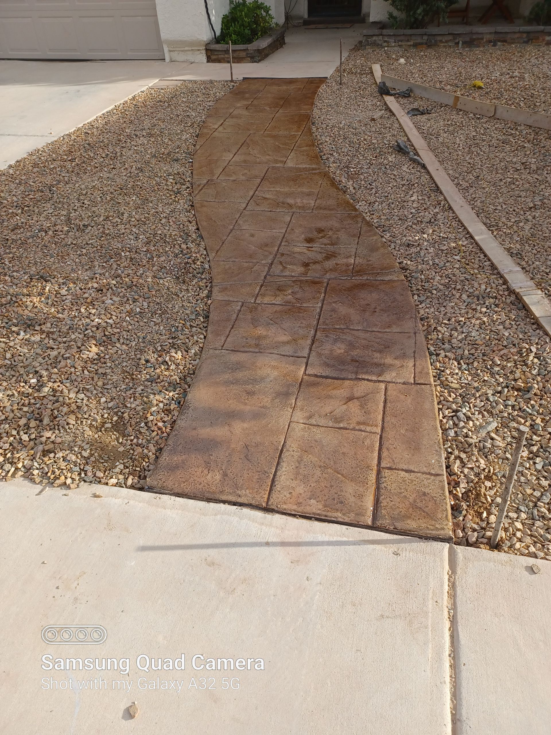 Stone walkway leading to a house surrounded by gravel.