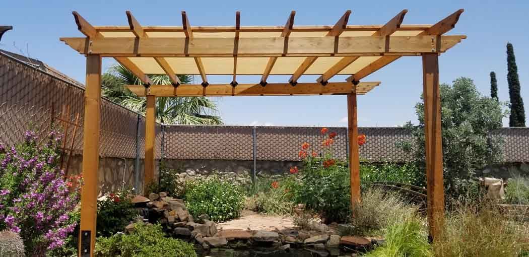 Wooden pergola with a fabric covering in a garden setting.