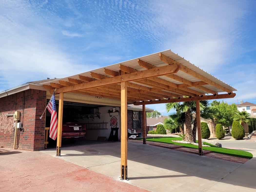 A wooden carport attached to a brick garage, with a car parked inside. An American flag hangs on the side.
