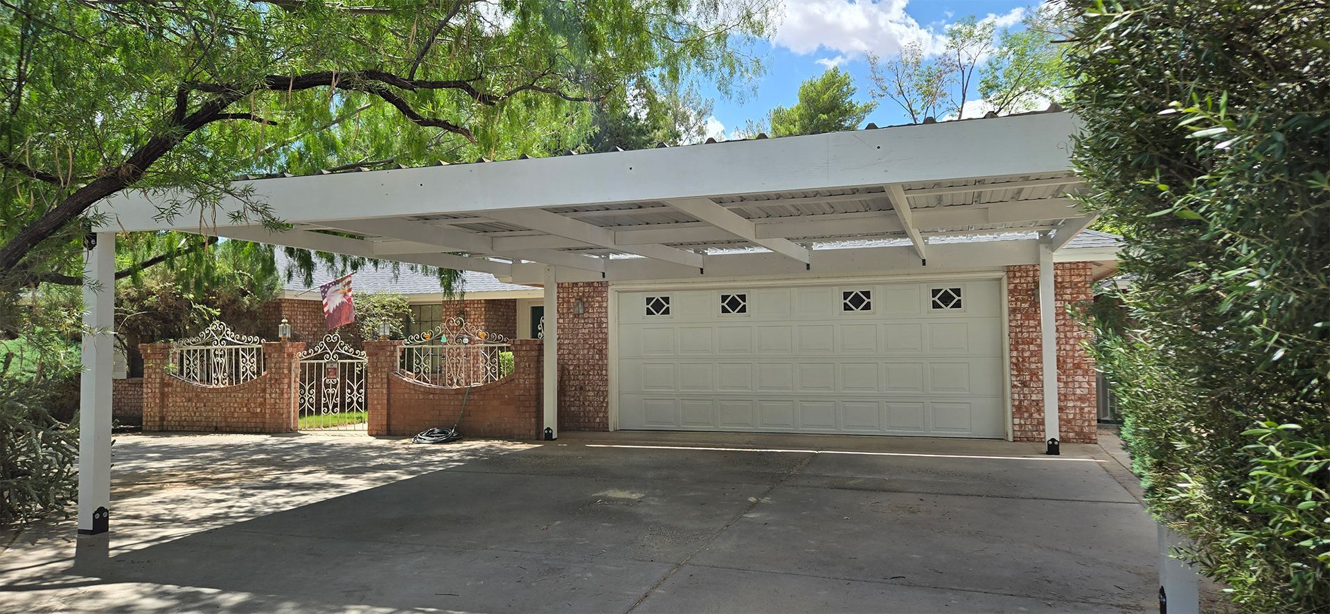 A carport leads to a brick building with a white garage door.