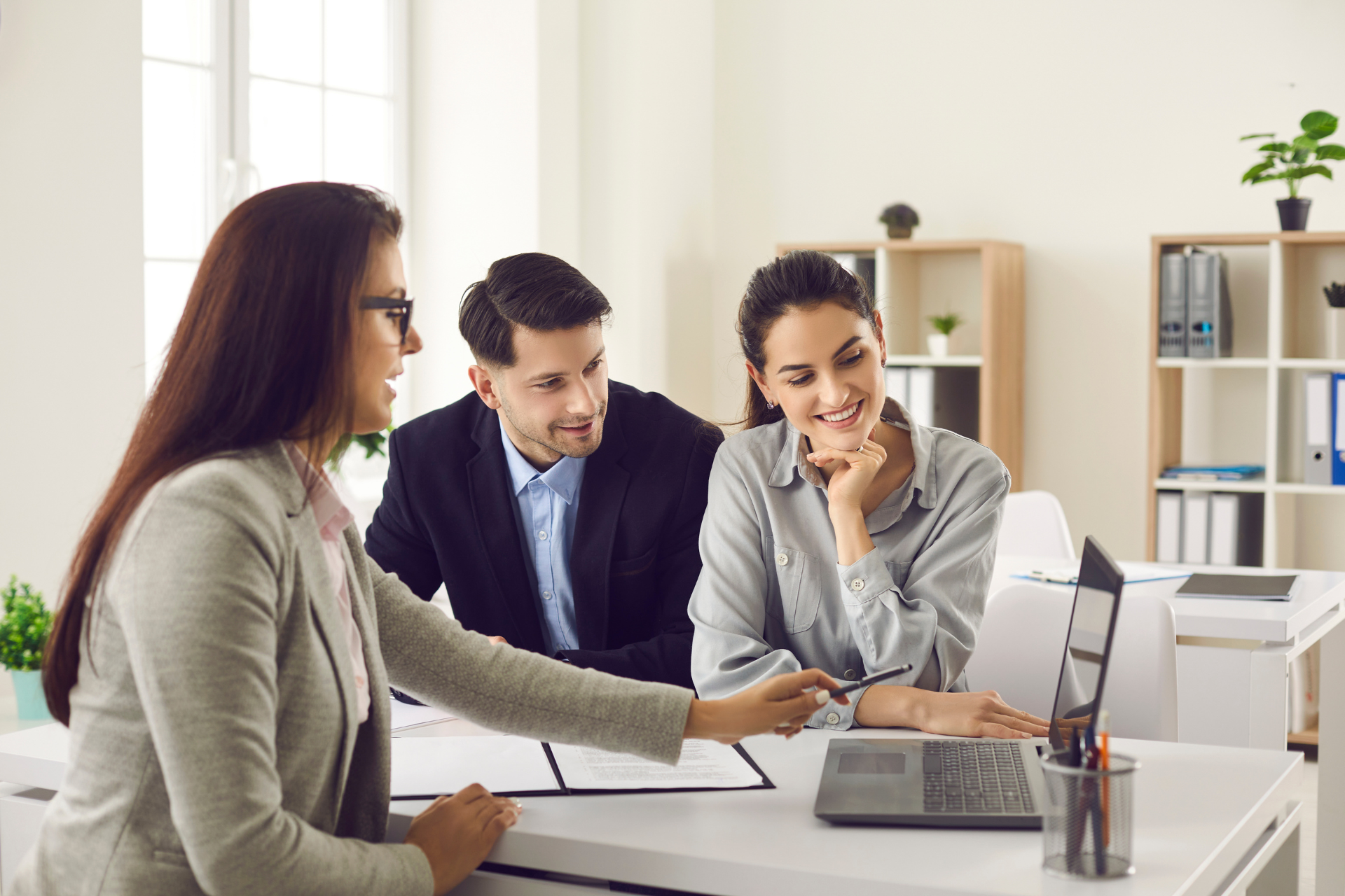 A man and a woman are sitting at a table looking at a laptop.