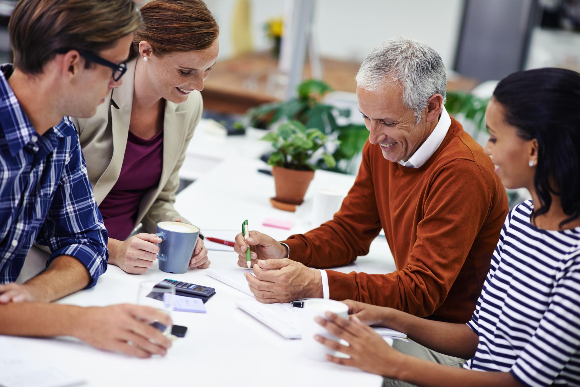 A group of people are sitting around a table having a meeting.