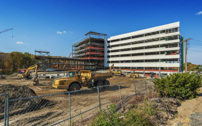 Construction site with partially built buildings, heavy machinery, and blue sky.
