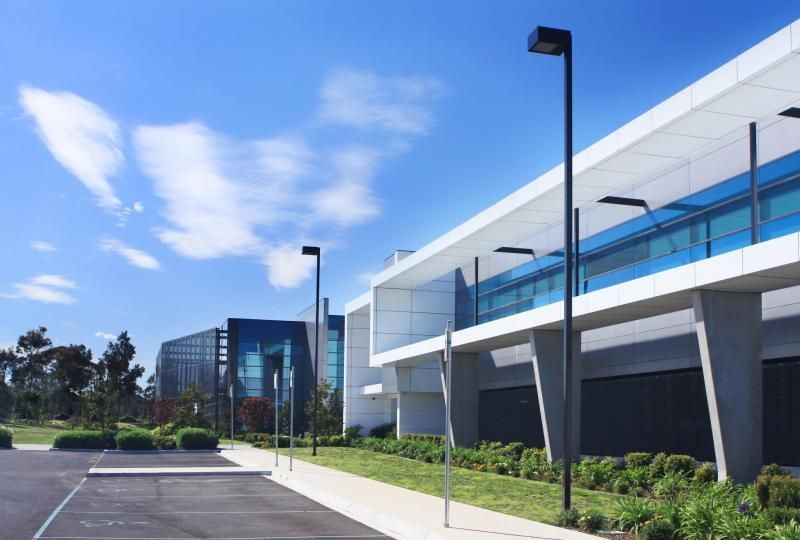 Modern office buildings with blue glass and white panels under a bright blue sky.