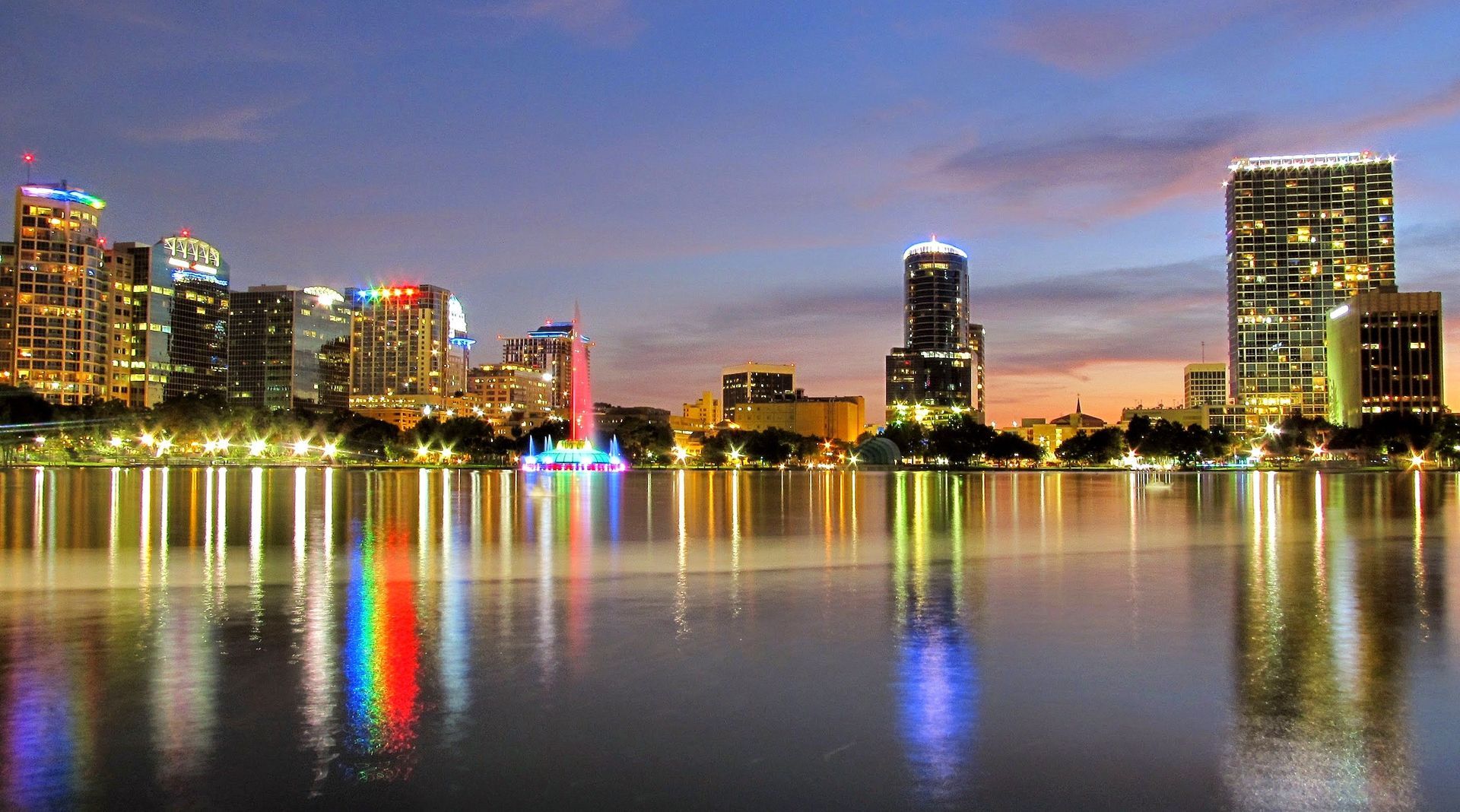 A city skyline is reflected in a lake at night.