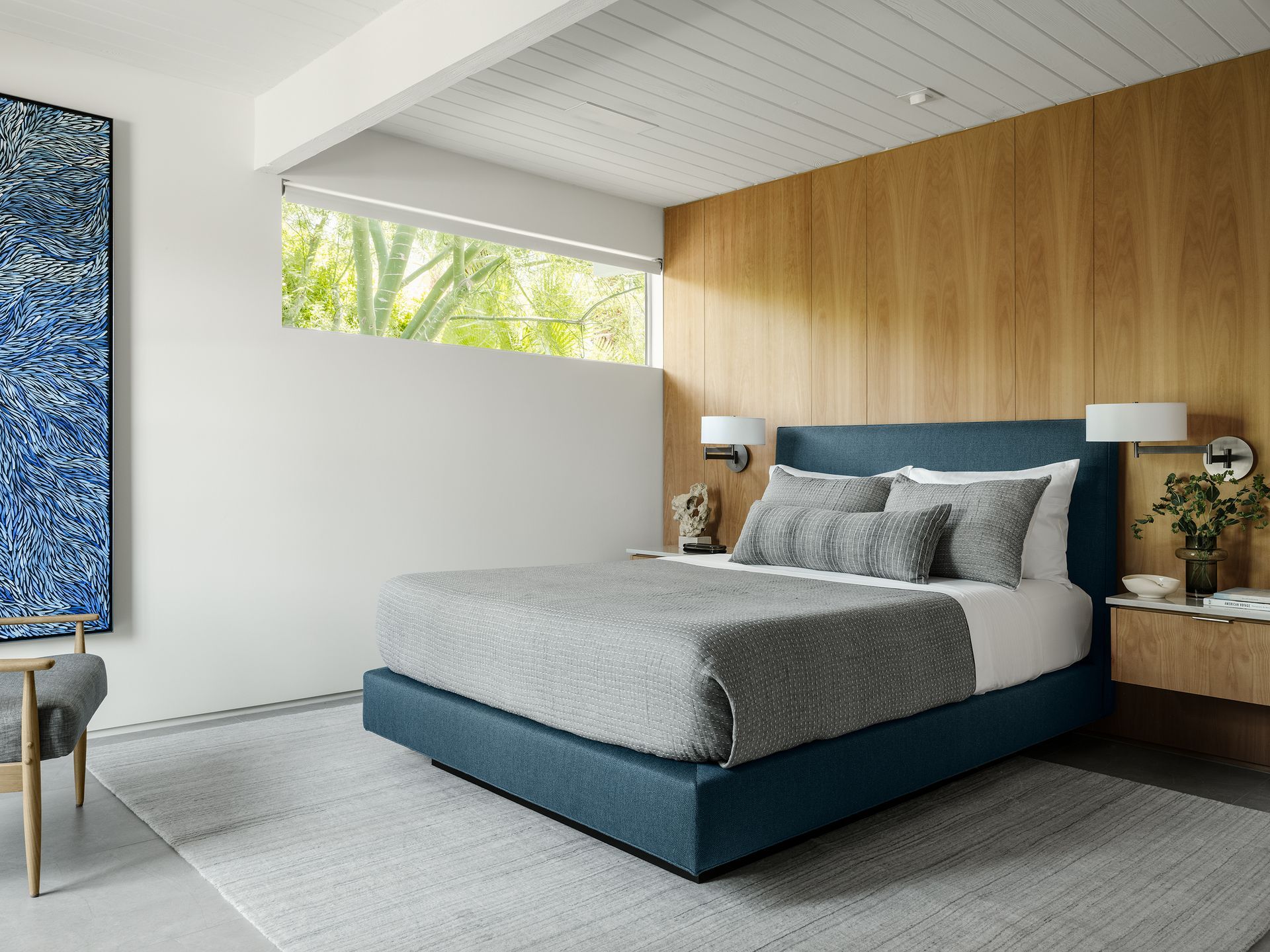 a bedroom with a bed , nightstand , chair and painting on the wall .