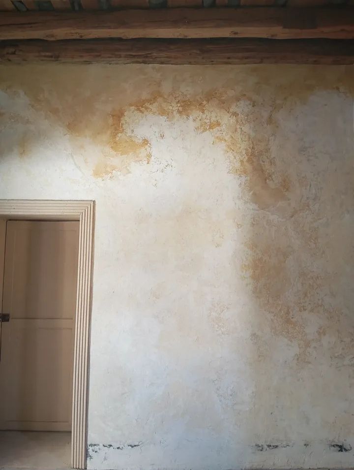 Una pared blanca con una puerta en una habitación con techo de madera.