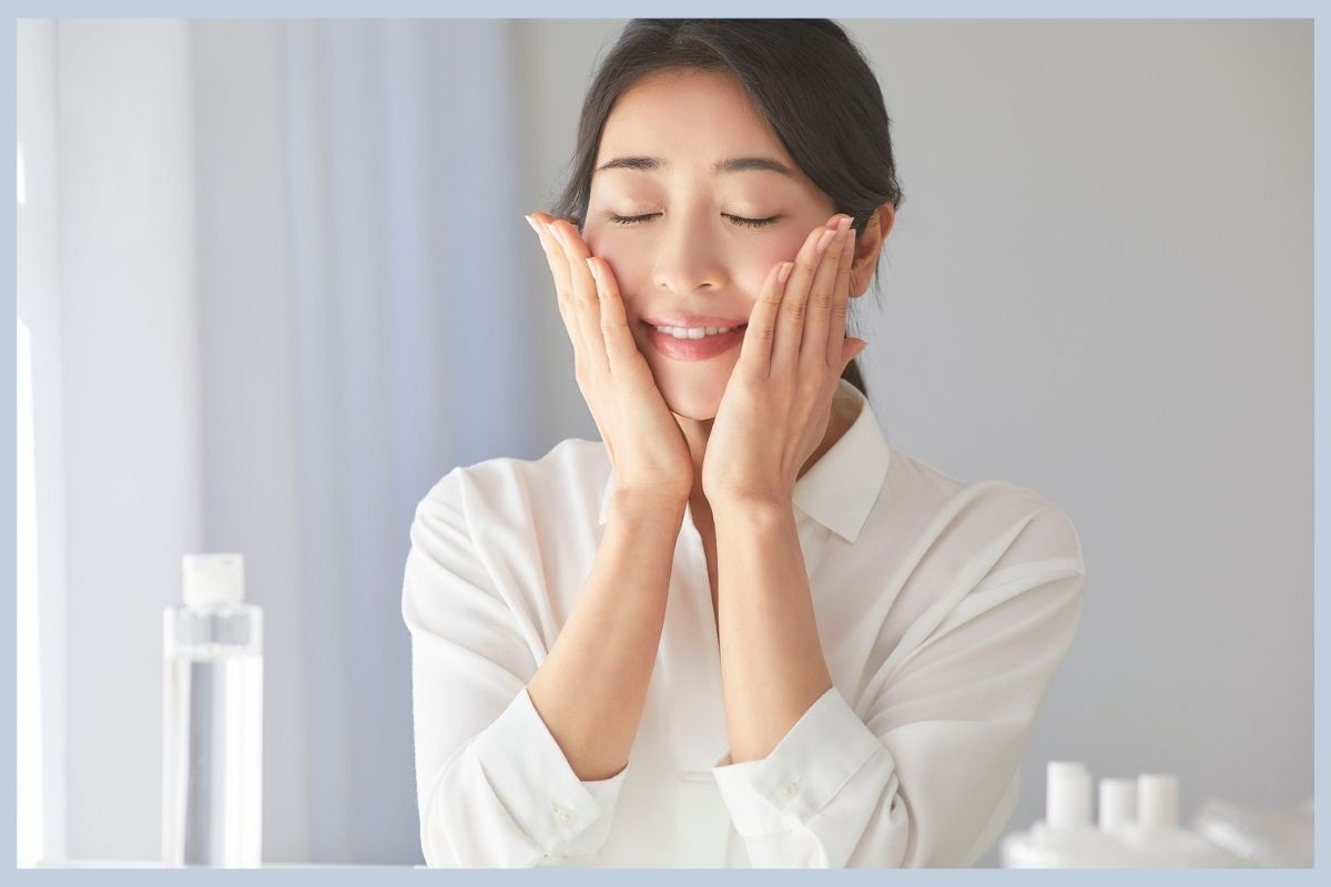 A woman examines her reflection in a mirror at a premier personalized medical care clinic.
