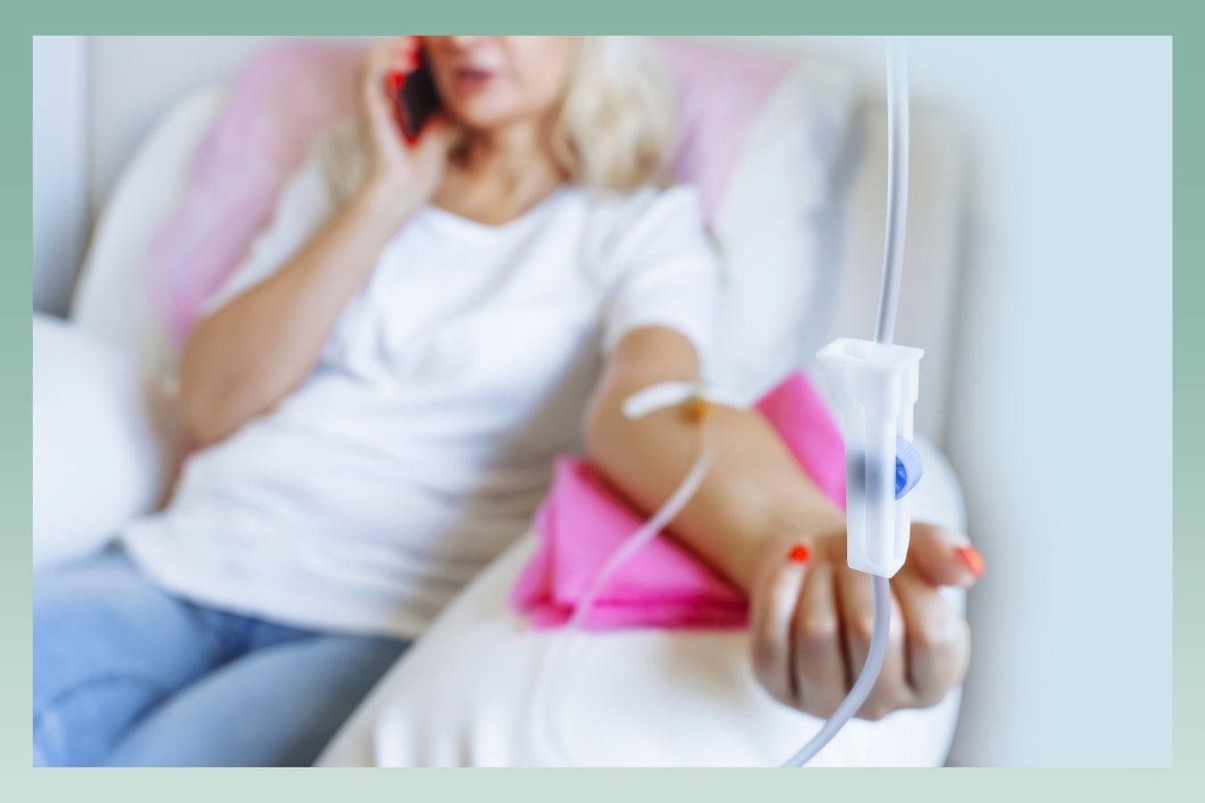 Woman receiving IV treatment while talking on the phone; in a light-filled room.