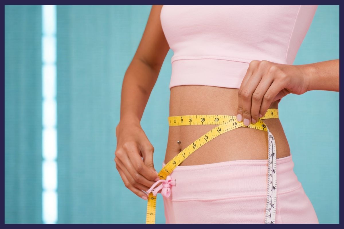A woman measuring her waist with a tape at a premier personalized medical care clinic.
